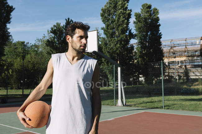 Homem com bola de basquete no chão de basquete — Fotografia de Stock