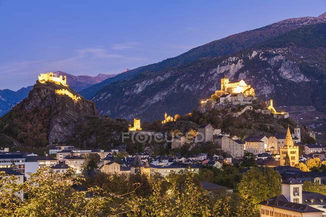Suiza, Canton Vaud, Sion, paisaje urbano con castillo de Tourbillon, Notre-Dame de Valere y Notre Dame du Glarier al atardecer - foto de stock