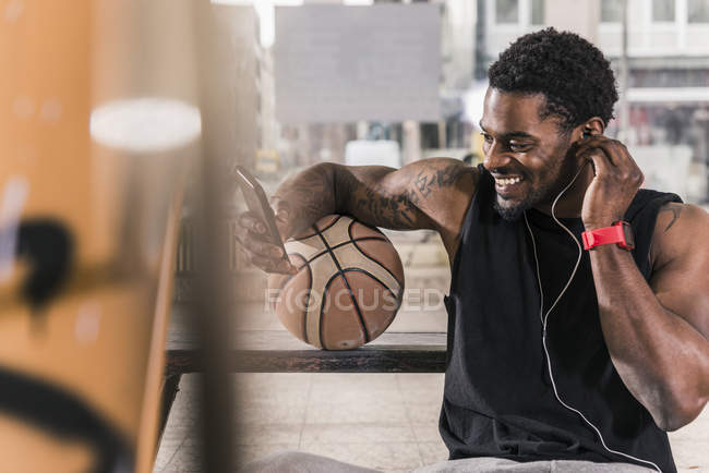 Esportivo com bola para jogar basquete, ouvindo música em fones de