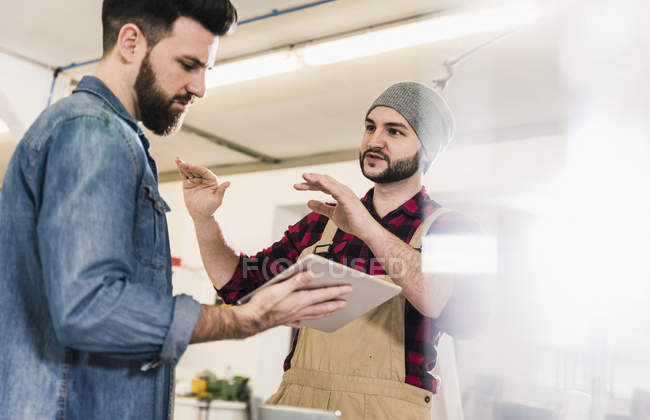 Zwei Männer mit Tablet diskutieren in Werkstatt — Stockfoto