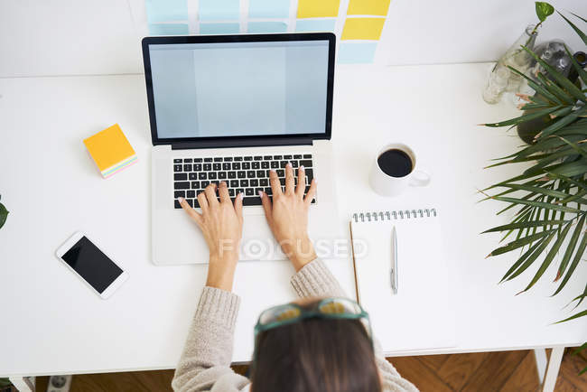 Young woman working at desk with laptop — Stock Photo
