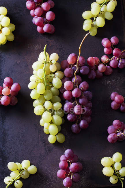 Grappoli freschi maturi di uva verde e rossa su fondo scuro — Foto stock