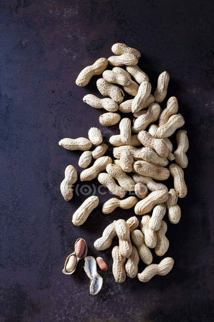 Whole and opened peanuts on rusty metal — Stock Photo