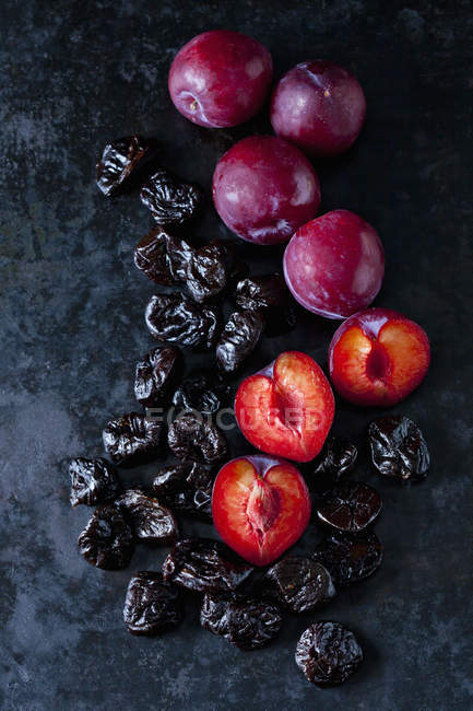 Fresh and dried plums on dark ground — Stock Photo
