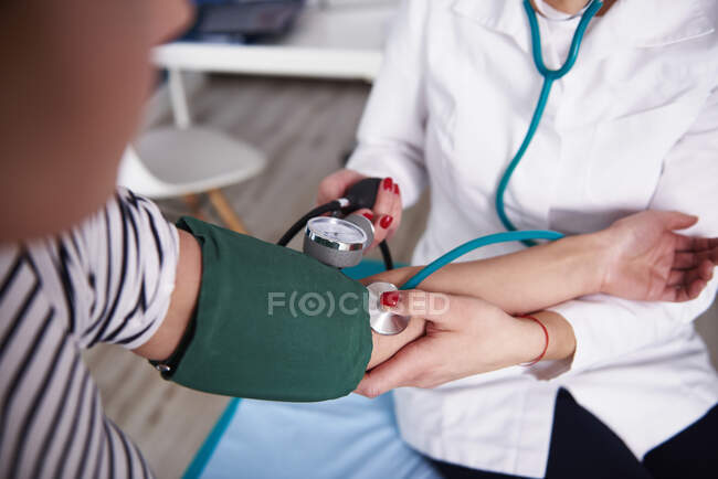 Doctor Taking Blood Pressure Of Woman In Medical Practice Cuff Young Adults Stock Photo