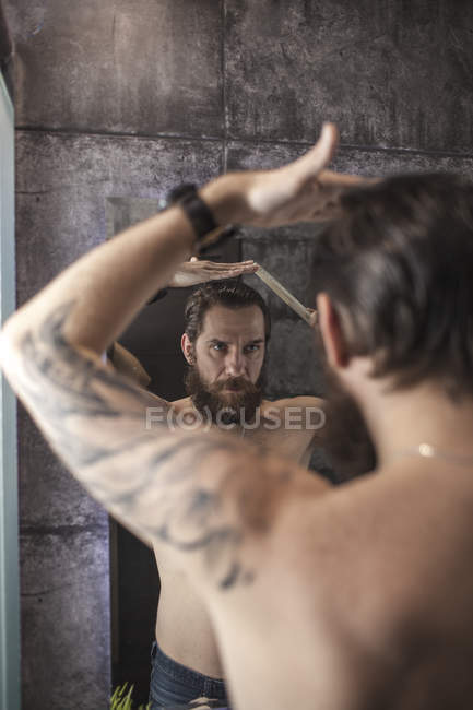 Портрет бородатого людини дивлячись на його дзеркальному зображенні при розчісування волосся — стокове фото