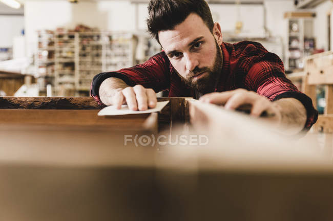 Людина лікування деревини в майстерні з пісочним папером — стокове фото
