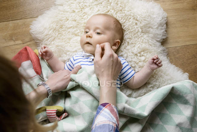 Madre che tocca il viso del neonato, sdraiato sulla pelle di agnello — Foto stock