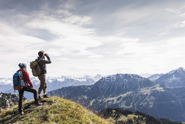 Austria, Tirol, pareja joven de pie en el paisaje de montaña y mirando a la vista - foto de stock