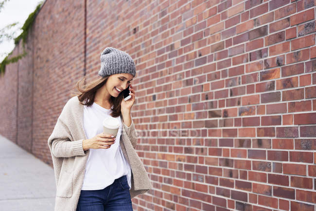 Femme heureuse avec café pour aller au téléphone — Photo de stock