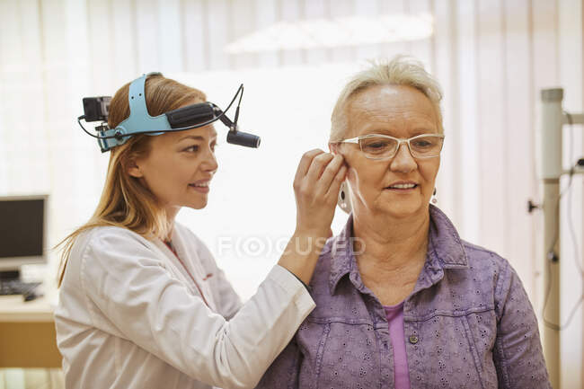 Otorrinolaringólogo examinando oído de una mujer mayor - foto de stock