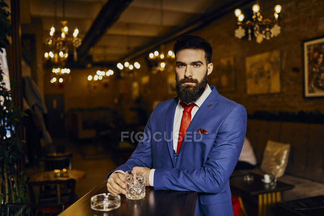 Portrait de jeune homme élégant dans un bar avec gobelet — Photo de stock