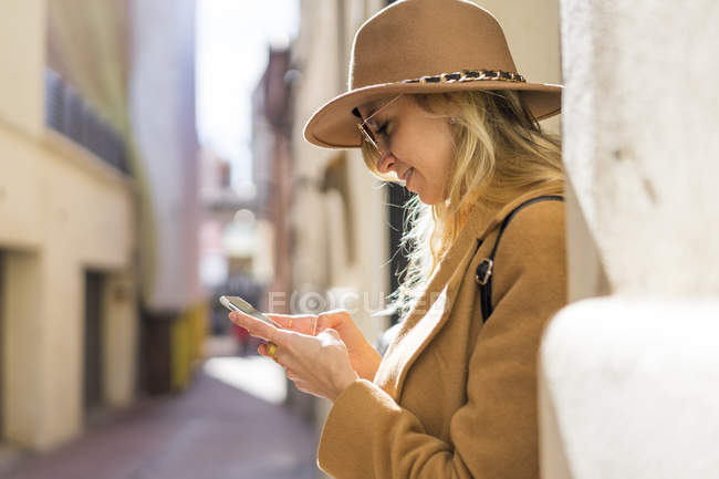 Модна молода жінка на смузі за допомогою мобільного телефону — стокове фото