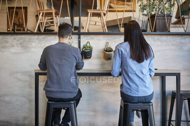 Vista trasera de la mujer joven y el hombre sentado en un café - foto de stock