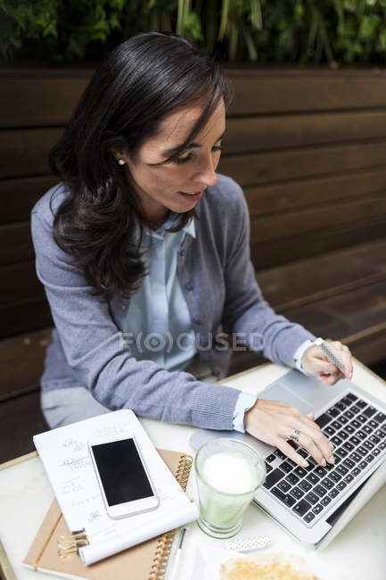 Femme d'affaires occupée travaillant sur un ordinateur portable dans un café en plein air — Photo de stock