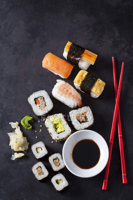 Variedad de sushi con wasabi, jengibre y bol de salsa de soja en tierra oscura - foto de stock