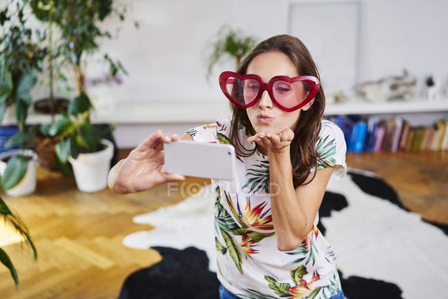 Young woman in heart-shaped glasses taking selfie — Stock Photo