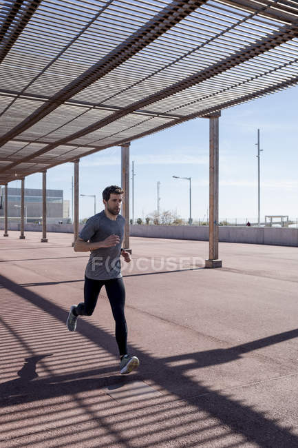 Sportive man runinng under roofing in the city — Stock Photo
