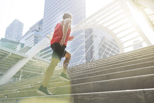 Uomo in camicia rossa fitness correre al piano di sopra in città — Foto stock