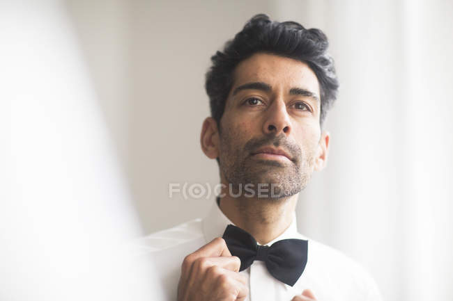 Handsome man adjusting his bow tie — Stock Photo