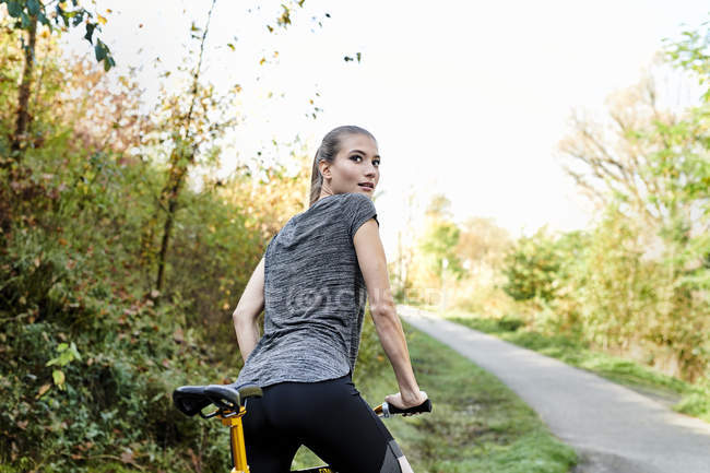 Vista trasera de la joven deportiva con bicicleta en un parque - foto de stock