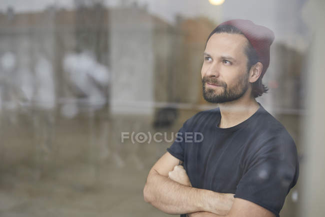 Portrait of thinking man with arms crossed wearing red hat and holding arms crossed — Stock Photo