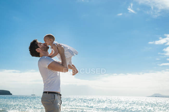 Spain, Lanzarote, father cuddling his little daughter on the beach — Stock Photo