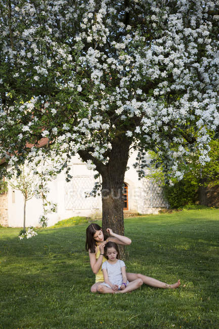 Deux filles assises devant un pommier en fleurs dans le jardin — Photo de stock