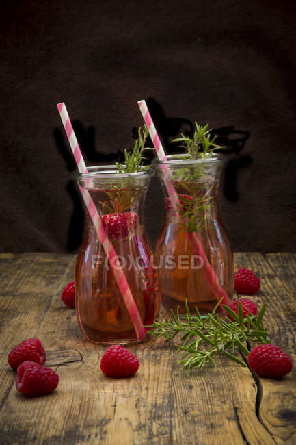Dos botellas de vidrio de limonada de frambuesa casera aromatizada con romero - foto de stock