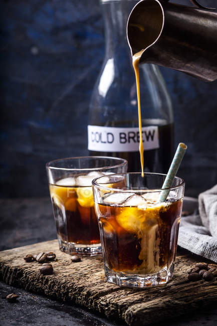 Hausgemachte Kaffeesahne mit Vanillearoma in ein Glas mit Eiskaffee gießen — Stockfoto