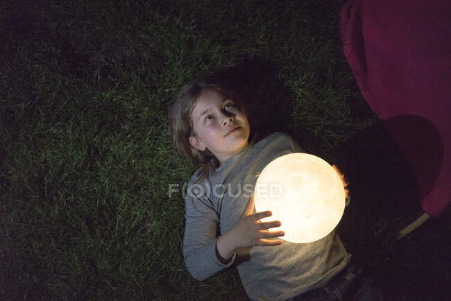 Mädchen liegt auf Wiese und hält Mond — Stockfoto