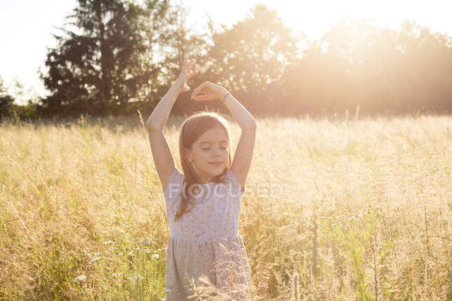 Jeune fille debout dans le champ le soir d'été — Photo de stock