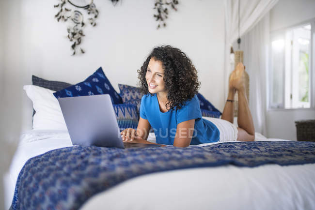 Усміхнена жінка лежала в ліжку за допомогою ноутбука — стокове фото