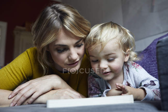 Ritratto di madre e figlioletta sul divano di casa — Foto stock
