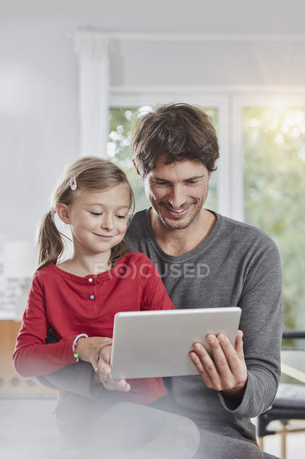 Sorridente padre e figlia utilizzando tablet a casa insieme — Foto stock