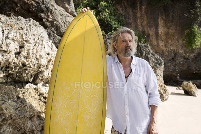 Hombre mayor cariñoso con tabla de surf en la playa - foto de stock