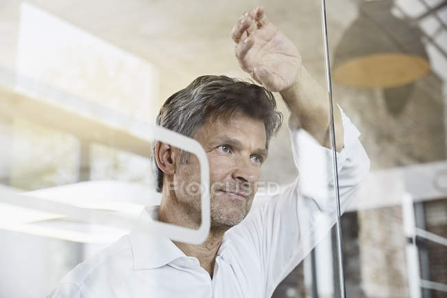 Портрет зрілої бізнесмена спираючись на скляну стіну в офісі — стокове фото