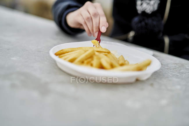 Женщина ест картошку фри, крупным планом — стоковое фото