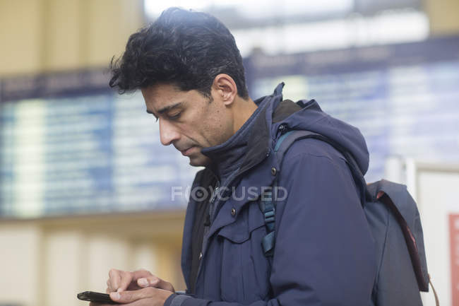 Uomo alla stazione ferroviaria usando il cellulare — Foto stock