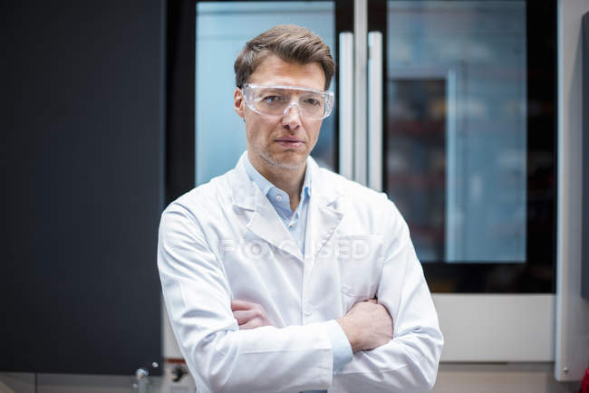 Portrait d'un homme portant une blouse de laboratoire et des lunettes de sécurité à la machine — Photo de stock