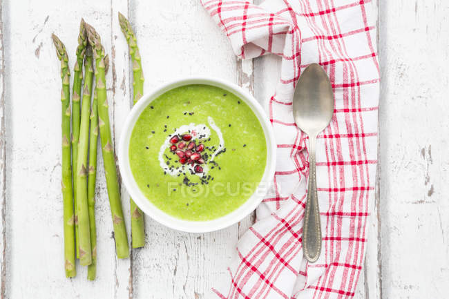 Green asparagus soup with pomegranate seeds and black sesame — Stock Photo