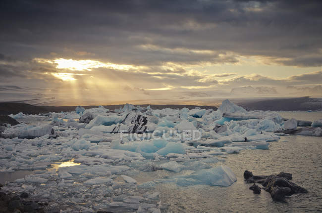 Iceland, South of Iceland, Joekulsarlon glacier lake, icebergs and sunshine through clouds — Stock Photo