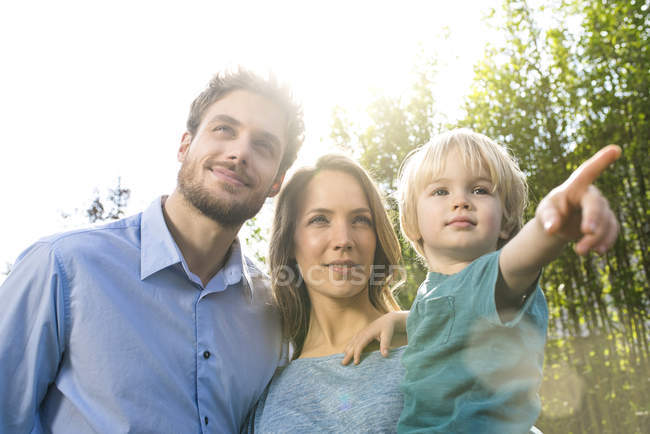 Famiglia sorridente di fronte a piante di bambù con figlio che punta il dito — Foto stock