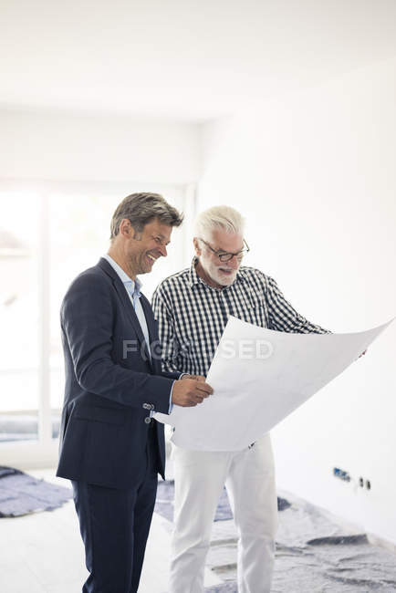 Happy man in suit and senior man looking at blueprint — Stock Photo