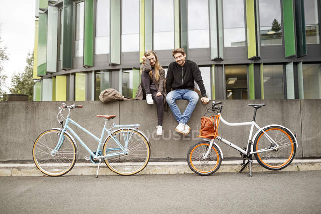 Щаслива пара з велосипедами сидять на стіні — стокове фото