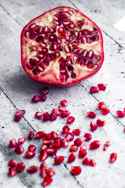 Sliced pomegranate and pomegranate seed on wood — Stock Photo