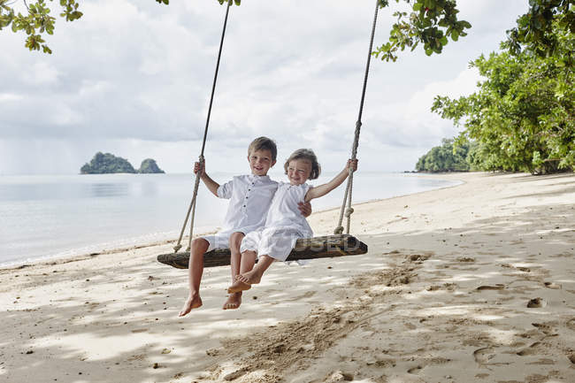 Thailand, Ko Yao Noi, happy boy and little girl on a swing on the beach — Stock Photo