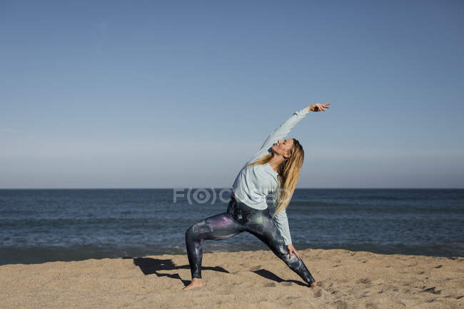 Femme faisant du yoga sur la plage — Photo de stock