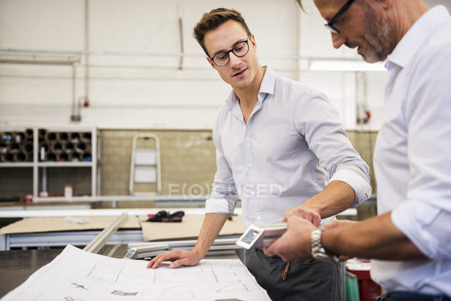 Dos hombres de negocios en fábrica discutiendo componente y plan - foto de stock