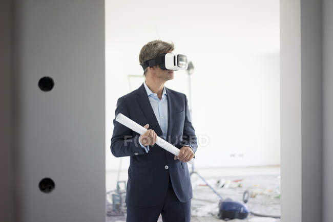 Man in suit wearing VR glasses in building under construction — Stock Photo